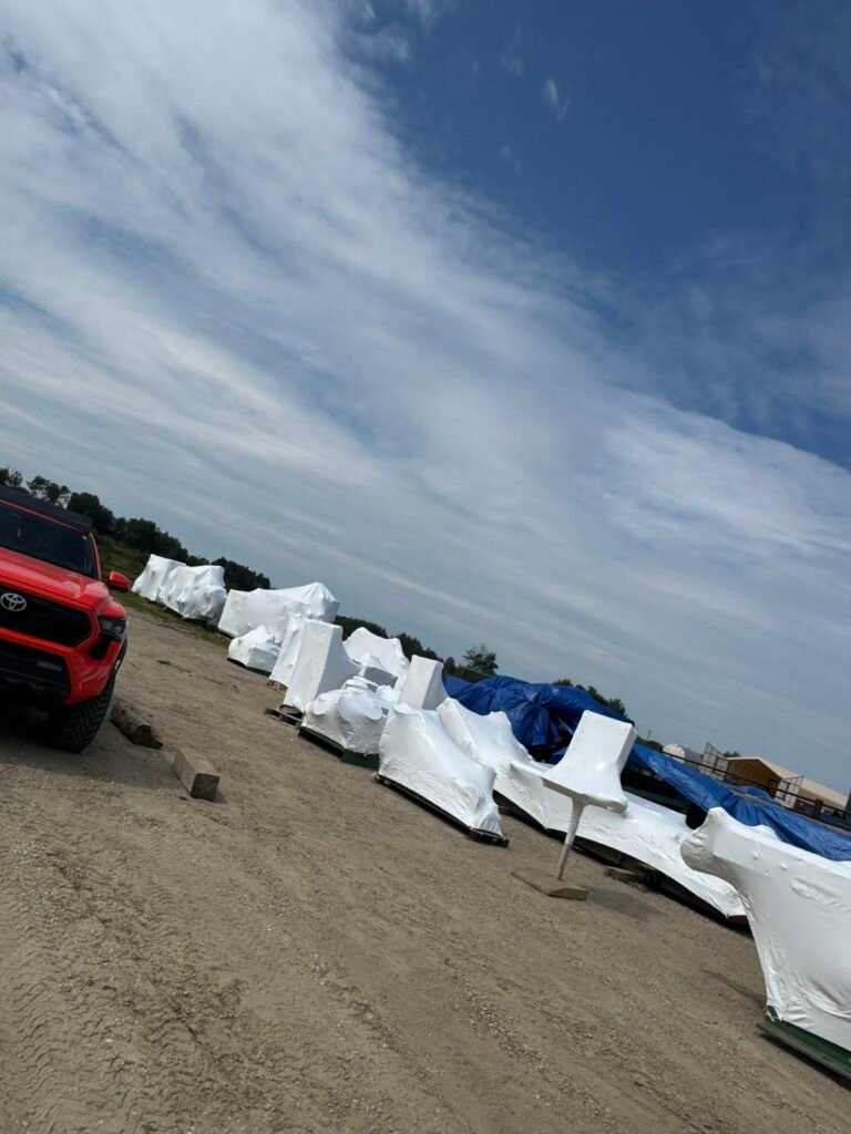 White shrink wrap protects multiple industrial loads beside a red truck in a yard.