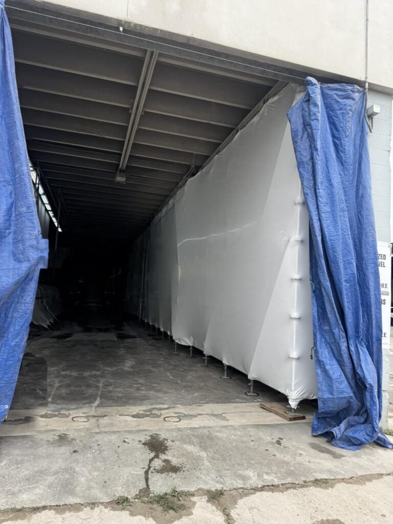A wall of white shrink wrap closes an open bay.